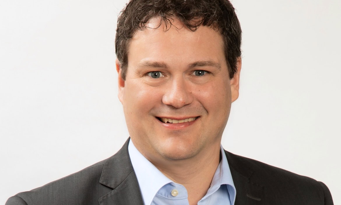 Mann im Anzug spricht bei Podcast über Policen und Maklerthemen.