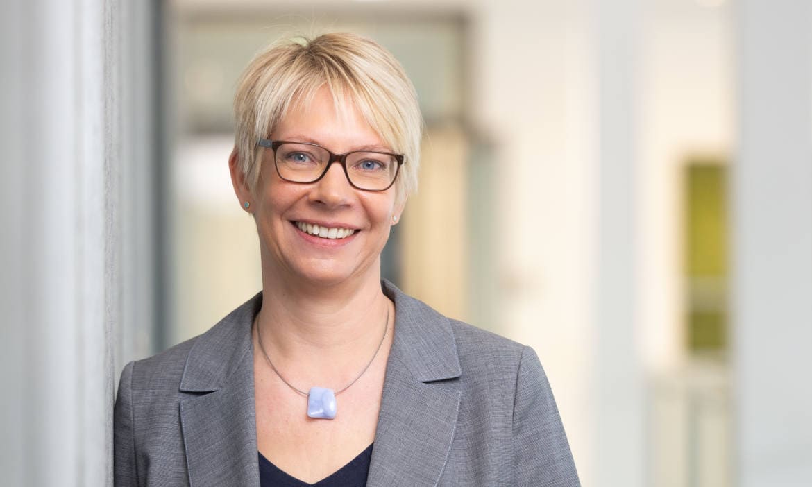 Professionelle Frau in Businesskleidung, lächelnd, im Büro.